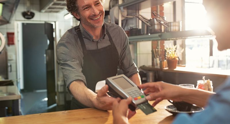 a imagem mostra um cliente e um comerciante recebendo por cartão de crédito.