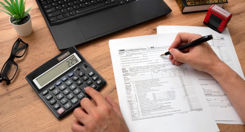 Pessoa fazendo contas com calculadora para entender o que muda nos impostos com a Reforma Tributária 2026