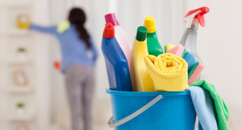 A imagem mostra um balde com produtos de limpeza, indicando o trabalho de uma empregada doméstica.