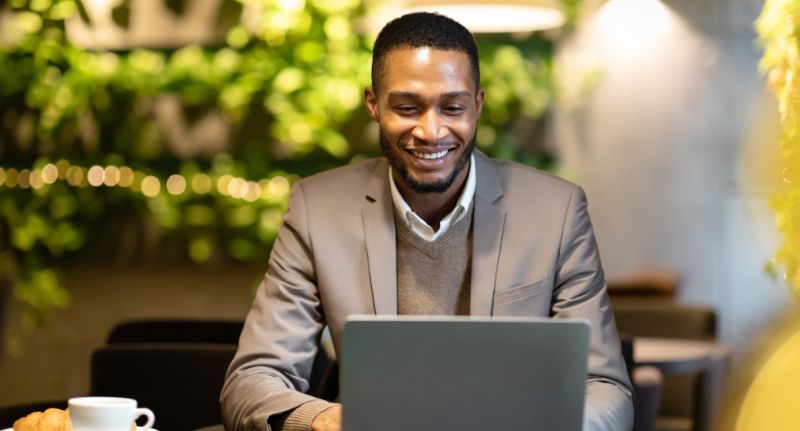 a imagem mostra um homem sorrindo e mexendo no notebook.