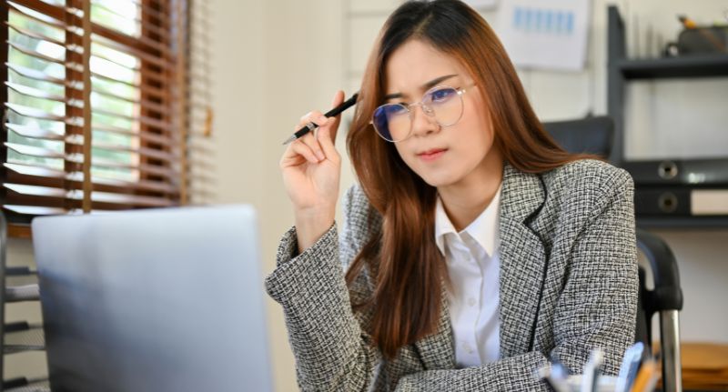 a imagem mostra uma mulher no computador pensativa sobre como cancelar nota fiscal MEI.