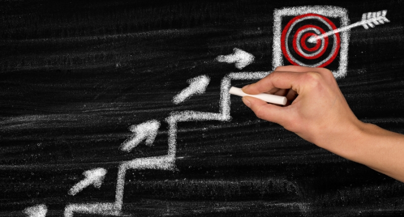 Quadro negro com desenho feito à giz mostrando uma escada ascendente, representando a progressão de metas.